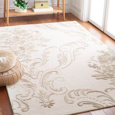 a white rug with an intricate design on it in a living room area next to a potted plant