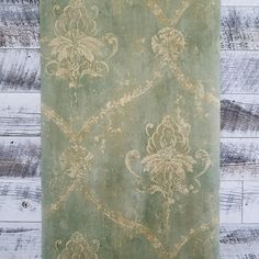 an old green rug with floral designs on wood planks in front of a white painted wall