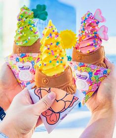 three ice cream cones with sprinkles are being held by someone's hands