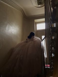 a woman in a white dress is walking up the stairs