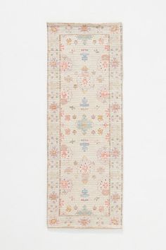 a white rug with flowers and leaves on the bottom is hanging up against a wall