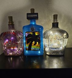 three different colored glass bottles sitting on top of a table