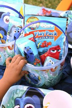 a child's hand is picking up some toys from a toy pail set