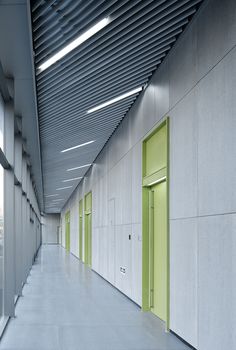 an empty hallway with green doors and white walls, in the middle of a building