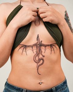 a woman with a dragon tattoo on her stomach is holding onto the side of her body