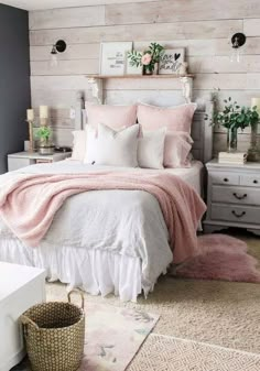 a bed with pink and white sheets in a bedroom next to a wall made out of wood planks