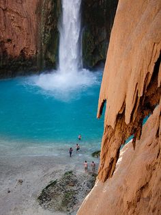 people are standing in front of a waterfall