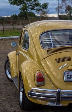 an old yellow car is parked in the dirt