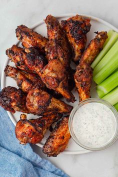 chicken wings with celery and ranch dressing on a white plate next to celery sticks