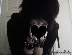 a woman with black hair holding her hands in front of her face and heart cutouts on the fingers