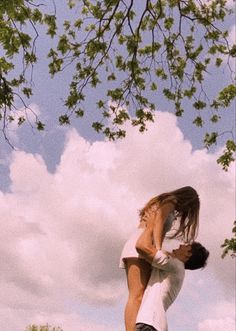 two people are standing in the grass with their arms around each other as they hug