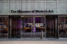 the museum of modern art is lit up with purple lights and people are walking by