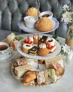 three tiered trays filled with pastries and desserts on top of a table