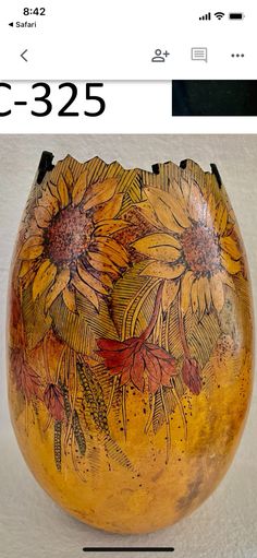 an orange vase with yellow flowers painted on it