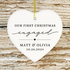 a heart shaped ornament with the words our first christmas engaged and matt's olvia on it