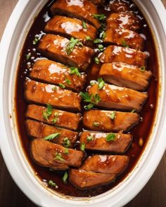 an overhead view of meat in a slow cooker with sauce and garnishes