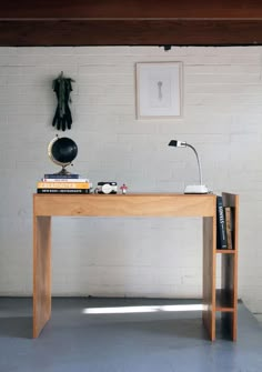 a wooden desk with books on it in front of a white brick wall and floor