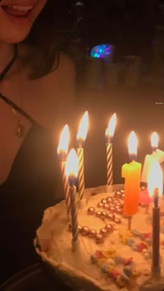 a woman holding a birthday cake with lit candles