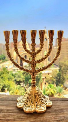 a golden menorah sitting on top of a wooden table in front of a city