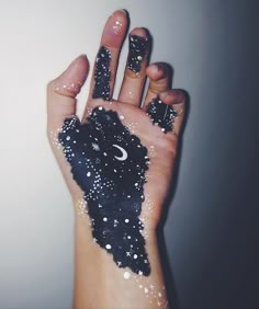 a person's hand painted with black and white glitters, holding an animal