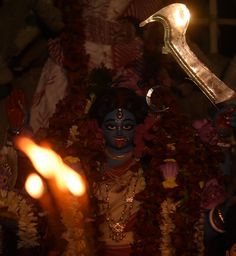 there is a lit candle in front of a statue that looks like lord haneshh