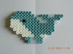 a piece of art made out of legos on a white surface with blue and white beads