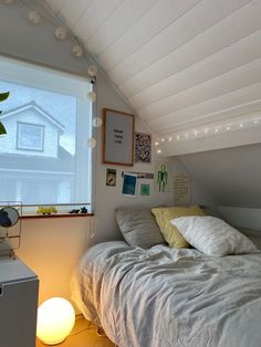 a bed sitting under a window next to a night stand with a lamp on it