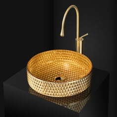 a golden sink with a faucet on the side and a black wall behind it