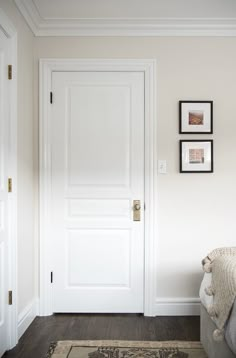 a white door with three pictures on the wall above it and a bed in front of it