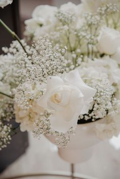 a vase filled with white flowers sitting on top of a glass table covered in baby's breath