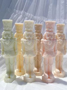 seven small figurines are lined up in a row on a white cloth background