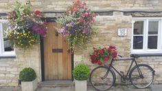 a bicycle parked in front of a building with flowers growing on it's windows