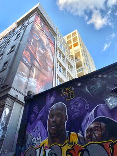 a large mural on the side of a building in front of a blue sky with clouds