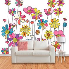 a white couch sitting in front of a wall with colorful flowers painted on it's side