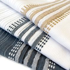 four folded towels stacked on top of each other in different colors and patterns, with one folded up to the side