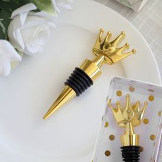 two gold and black wine stoppers sitting on top of a white plate next to flowers