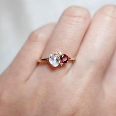 a woman's hand holding an engagement ring with two stones on it, and the middle