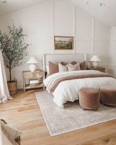 a bedroom with white walls and wood flooring has a large bed in the corner