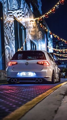 a white car parked in front of a building with christmas lights on it's side