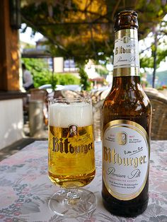 a bottle and glass sitting on top of a table next to each other with a beverage in front of it