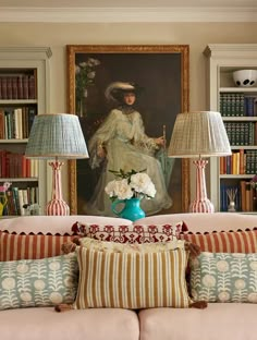 a living room filled with lots of furniture next to bookshelves and a painting on the wall