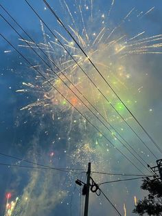 fireworks are lit up in the sky above power lines