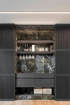 a room with black and white marble walls, wooden flooring and shelves filled with glassware