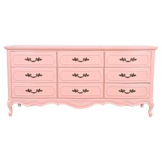 a pink dresser with gold handles and drawers on it's sides, against a white background