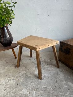 two small wooden stools next to a potted plant on top of a table