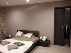 a bedroom with a bed, dresser and closet in the corner next to it is lit by recessed lights