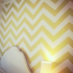 a white bed sitting next to a wall with yellow chevrons on the walls