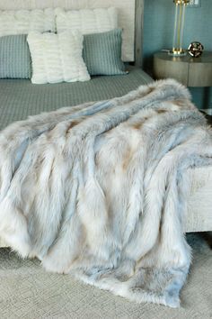 a bed with a fur blanket on top of it next to a night stand and nightstand