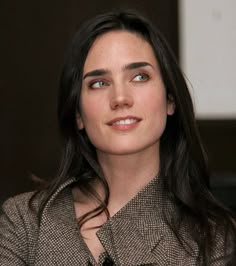 a close up of a person wearing a suit and tie with a smile on her face