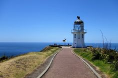 a white lighthouse sitting on top of a hill next to the ocean